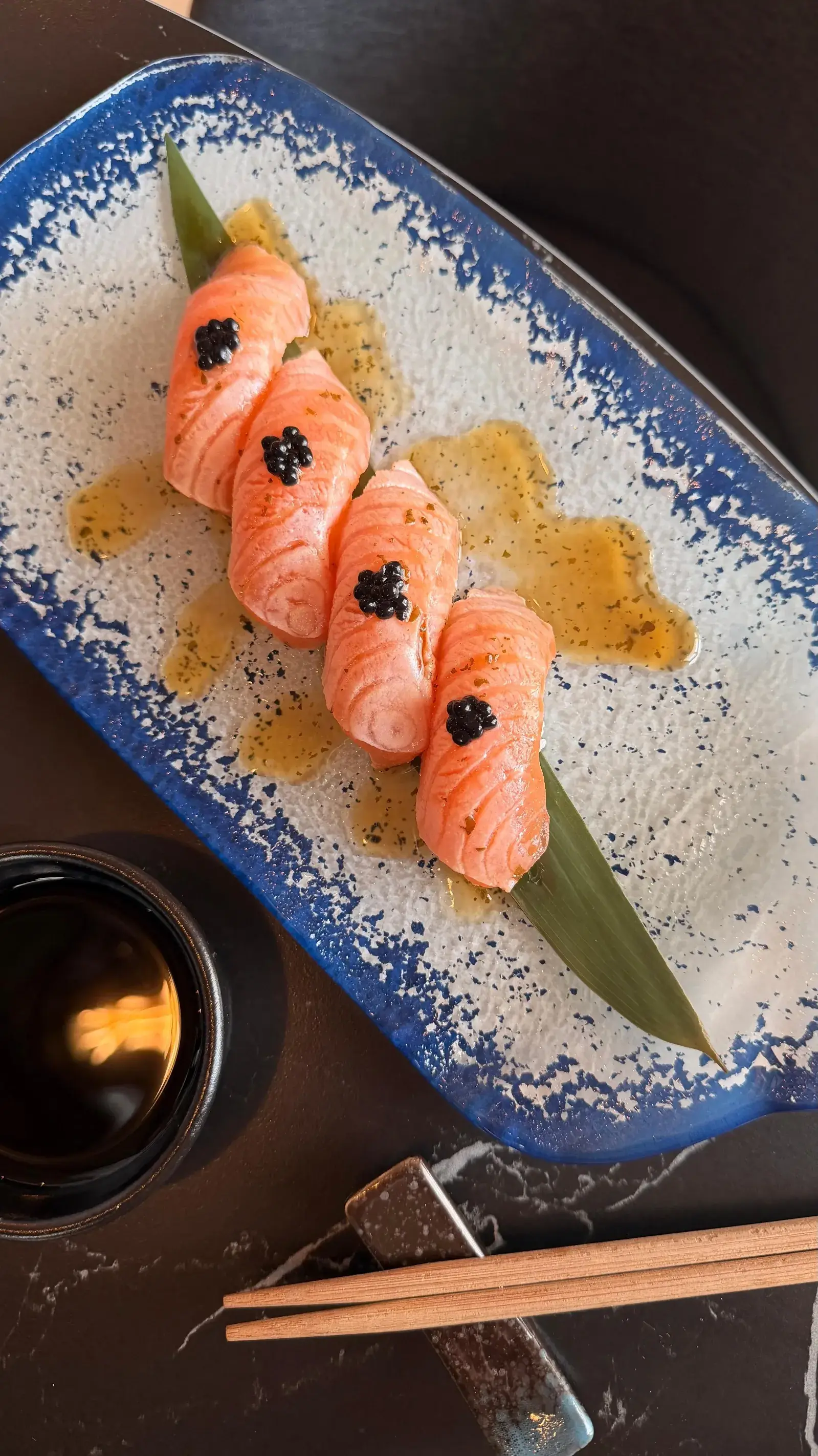 Piezas de nigiri de salmón sobre una superficie oscura